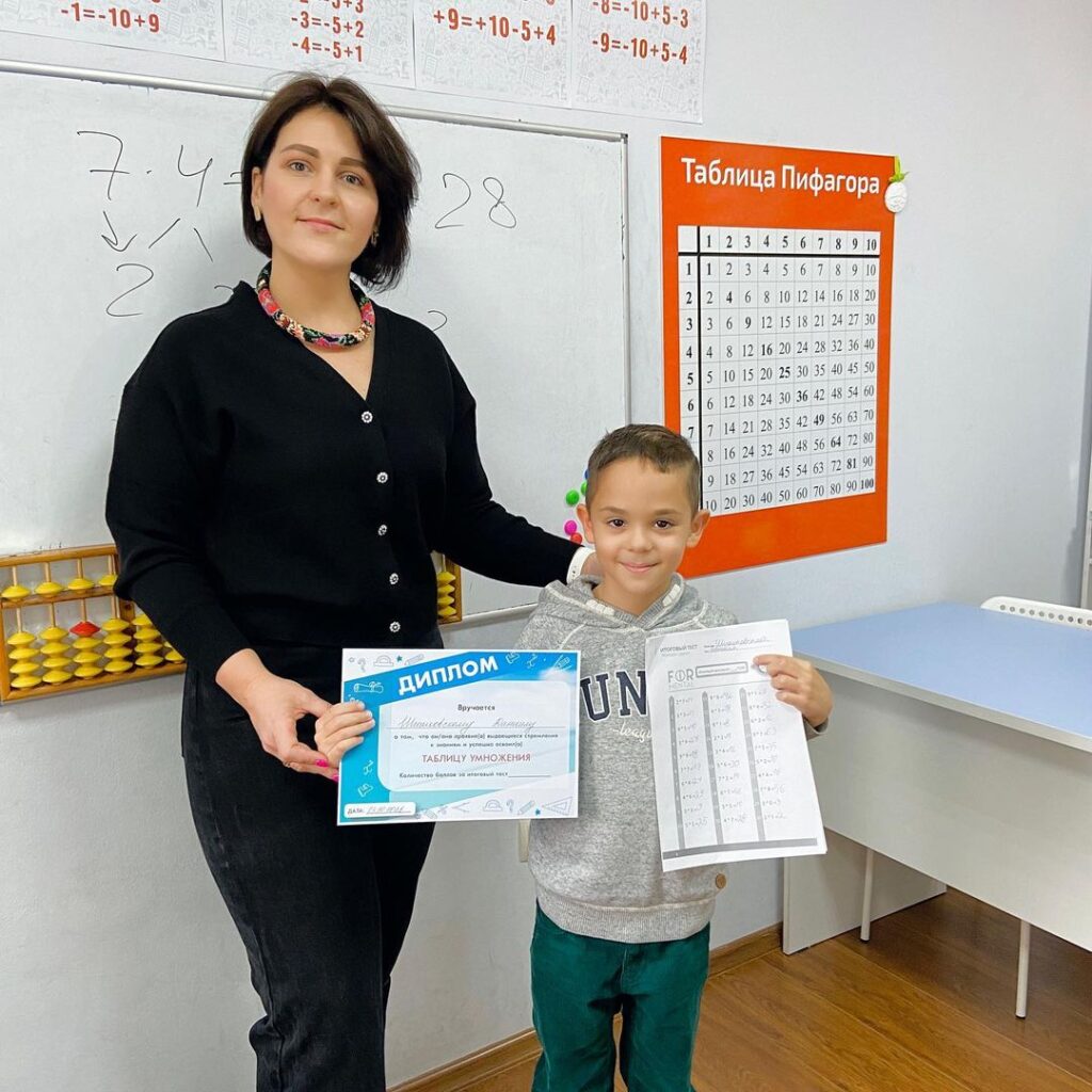 Педагог награждает ученика дипломом за курс таблицы умножения